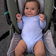 Boyan is registered to the contest to win money with this photo: baby, infant, child, car_seat, onesie, smiling, face, blue_clothing, cushion, seat, safety, happy, person, cute, young, indoors, soft_texture, hand, legs, head
