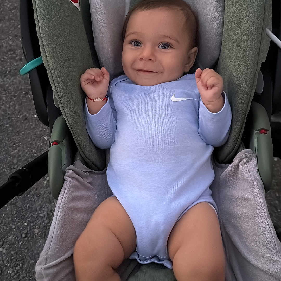 Boyan is registered to the contest to win money with this photo: baby, blue_clothing, car_seat, child, cushion, cute, face, hand, happy, head, indoors, infant, legs, onesie, person, safety, seat, smiling, soft_texture, young