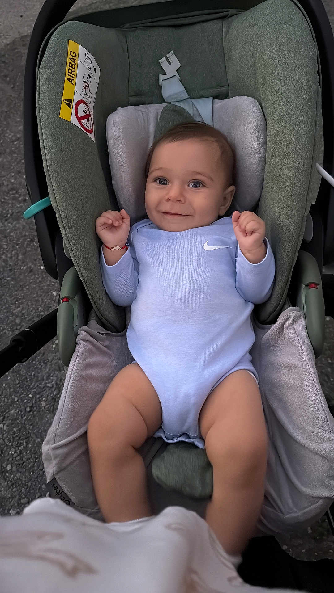 Boyan is registered to the contest to win money with this photo: baby, infant, child, car_seat, onesie, smiling, face, blue_clothing, cushion, seat, safety, happy, person, cute, young, indoors, soft_texture, hand, legs, head