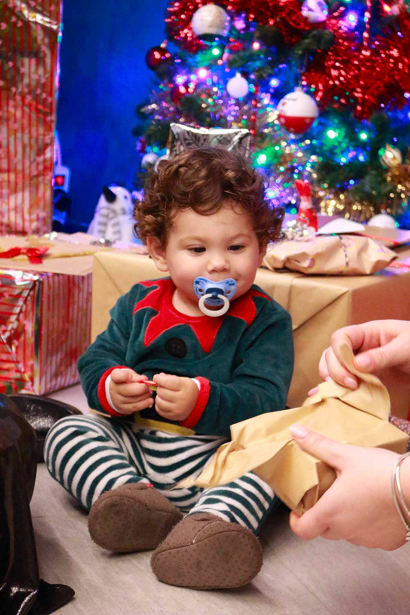 Arsène a rejoint le concours — aidez-le/la à gagner de superbes lots ! baby, child, christmas, christmas_decoration, christmas_eve, christmas_ornament, christmas_tree, event, fun, happy, holiday, lap, leisure, ornament, person, sitting, smile, sock, toddler, tree