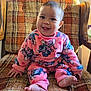 Kaori Delgado is registered to the contest to win money with this photo: baby, child, smiling, pink_clothing, cartoon_pattern, plaid_chair, vintage_furniture, happy, indoors, cute, sitting, bare_feet, face, person, cozy, warm, patterned, wooden_armrest, portrait, infant
