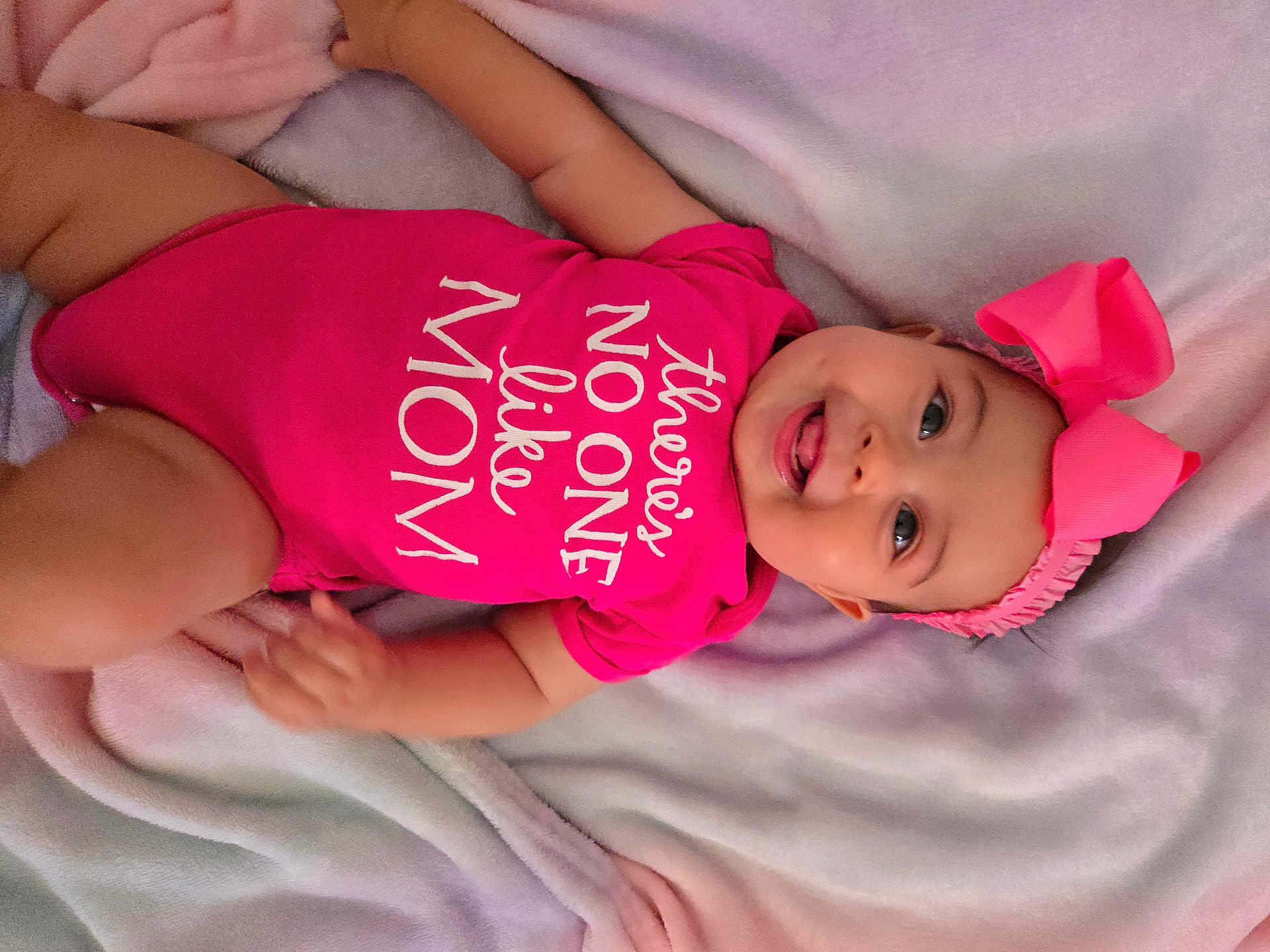 Kaori Hinata Delgado joined the competition — help win amazing prizes! baby, child, pink_onesie, headband, bow, smiling, tongue_out, blanket, infant, cute, happy, portrait, lying_down, soft_texture, fabric, clothing, face, person, baby_girl, playful