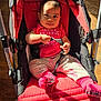 baby, child, stroller, red, pink, clothing, indoor, floor, sunlight, holding, straps, pants, socks, happy, cute, person, infant, seat, playful, smiling