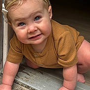 Journey is registered to the contest to win money with this photo: baby, child, crawling, headband, blue_eyes, brown_clothing, doorway, hands, floor, indoor, closeup, cute, infant, person, skin, smiling, young_child, portrait, happy, natural_light