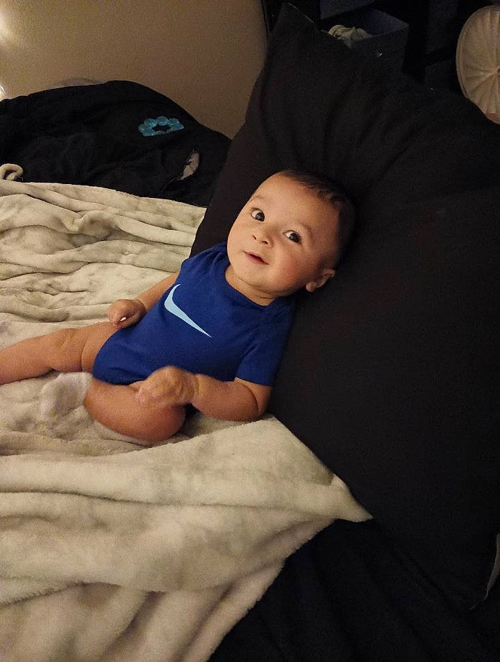 Dax is registered to the contest to win money with this photo: abdomen, baby, baby_toddler_clothing, cheek, child, comfort, elbow, facial_expression, finger, flash_photography, fun, human_leg, linens, mouth, person, sitting, skin, t_shirt, textile, toddler