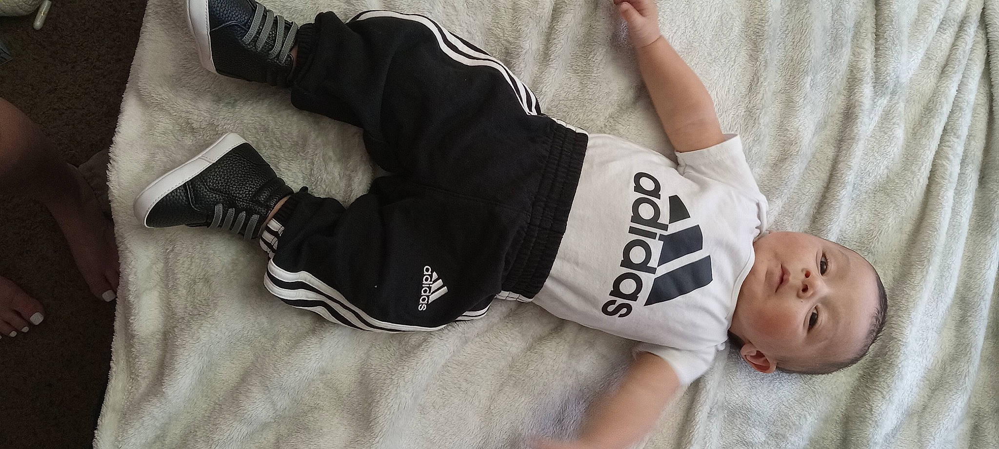 Dax is registered to the contest to win money with this photo: baby_toddler_clothing, chest, comfort, elbow, fashion_accessory, font, gesture, human_leg, jersey, knee, leg, pattern, person, personal_protective_equipment, sleeve, sports_gear, sportswear, t_shirt, thigh, waist