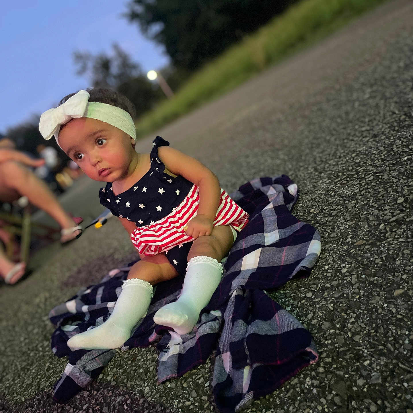 Brexley joined the competition — help win amazing prizes! asphalt, baby, blanket, bow, child, dress, evening, grass, headband, outdoor, person, plaid, portrait, sitting, socks, stars, stripes, toddler, trees, twilight