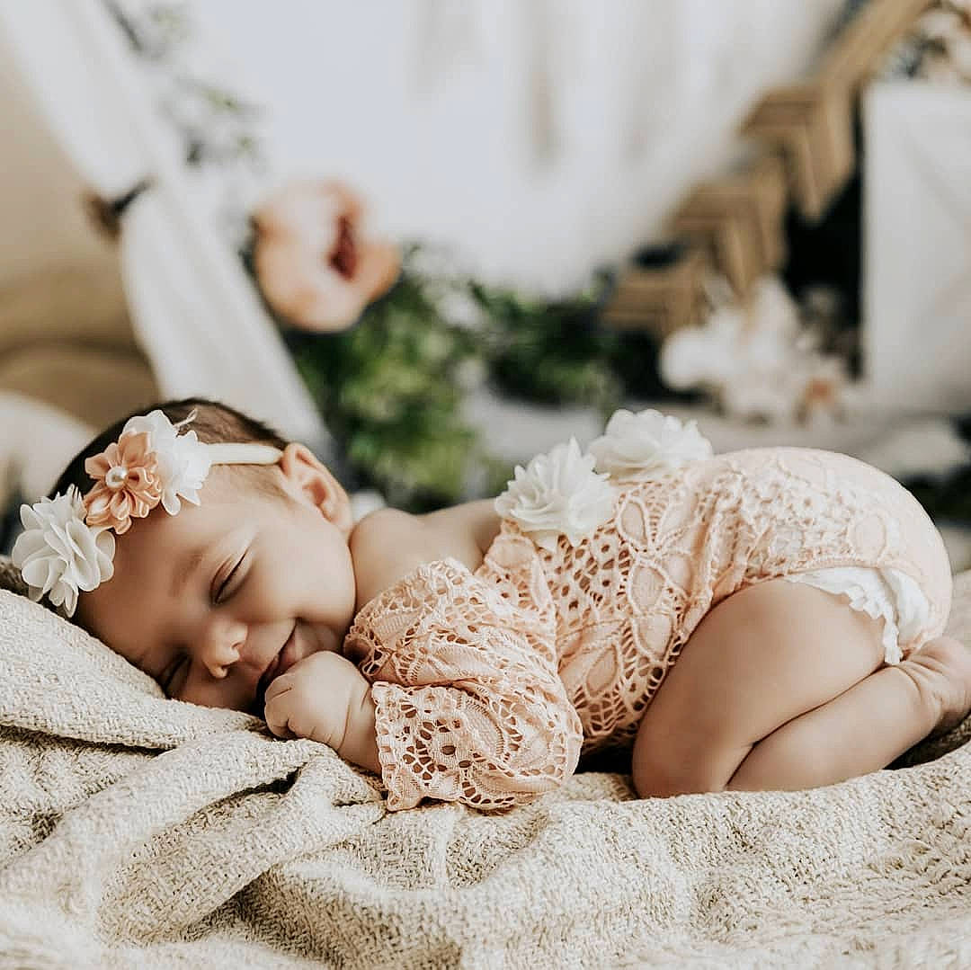 Rhea is registered to the contest to win money with this photo: arm, baby, baby_sleeping, baby_toddler_clothing, child, comfort, eye, flash_photography, gesture, grass, happy, head, headpiece, headwear, human_leg, jewellery, leg, person, sitting, skin