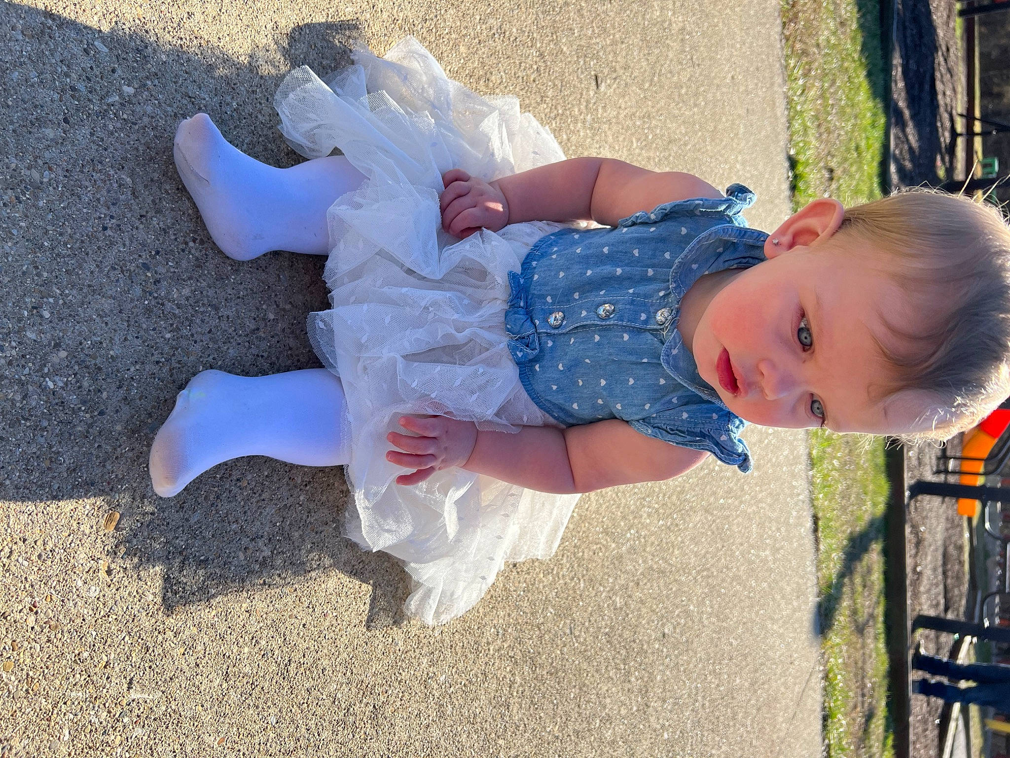 Oaklynn is registered to the contest to win money with this photo: baby, baby_toddler_clothing, barefoot, child, dress, foot, fun, gesture, grass, happy, human_leg, leg, leisure, pattern, people_in_nature, person, play, sitting, smile, toddler