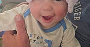 Zayden is registered to the contest to win money with this photo: adult, arms, baby, car, child, close_up, cuddling, dinosaur_clothing, family, happy, headband, indoor, infant, joy, onesie, parent, pink_bow, portrait, smiling, vehicle