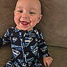 baby, child, infant, smiling, happy, portrait, superman, superhero, pajamas, onesie, couch, sitting, indoors, face, eyes, mouth, hand, clothing, close_up, photography