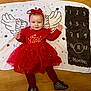 angel_wings, baby, blanket, celebration, child, christmas, clothing, cute, festive, floor, footwear, happy, headband, indoors, milestone, numbers, portrait, red_dress, smiling, toddler