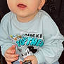 baby, child, blue_eyes, mickey_mouse, sweatshirt, hand, face, stroller, seat, curious, clothing, person, infant, holding, casual, cute, portrait, sitting, indoor, young