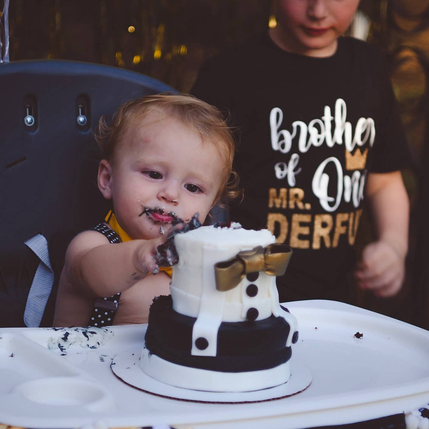 Ryker is registered to the contest to win money with this photo: baked_goods, birthday_cake, cake, cake_decorating, cake_decorating_supply, child, clothing, cuisine, dessert, food, fun, person, plate, product, shirt, smile, sugar_cake, t_shirt, table, toddler