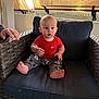 Dylan is registered to the contest to win money with this photo: baby, toddler, child, sitting, wicker_chair, cushion, red_shirt, nike_logo, mickey_mouse_pants, barefoot, indoor, blinds, sunset_light, left_hand, portrait, curious_expression, face, pajama_pants, home, cozy
