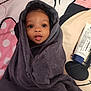 Samantha is registered to the contest to win money with this photo: baby, towel, face, eyes, bedspread, lotion, skin, comfort, infant, wrapped, mouth, tongue, soft, cute, indoors, child, person, expression, blanket, head