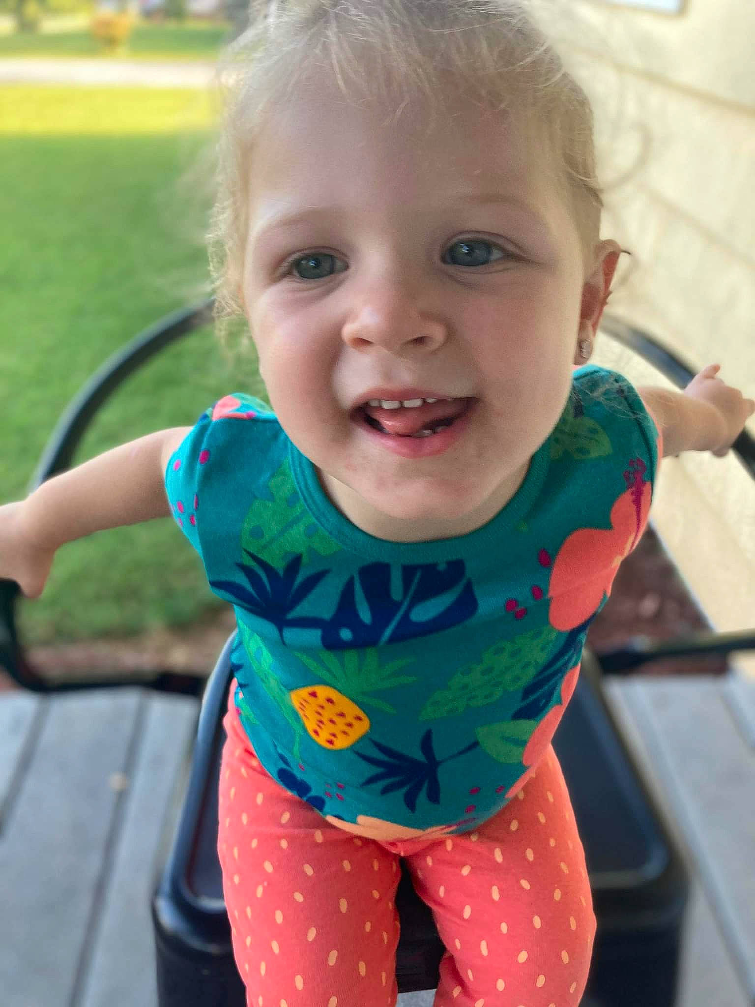 Diana is registered to the contest to win money with this photo: baby, baby_toddler_clothing, cheek, eye, face, facial_expression, finger, grass, happy, head, iris, neck, person, pink, product, skin, sleeve, smile, standing, t_shirt