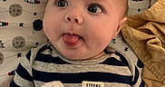 Zaliyah joined the competition — help win amazing prizes! baby, infant, striped_shirt, mittens, face, tongue_out, teddy_bear, blanket, space_theme, pillow, cute, lying_down, soft_toys, child, playful, clothing, person, indoor, expression, newborn