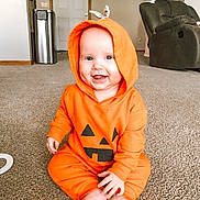 Brae joined the competition — help win amazing prizes! baby, infant, orange_hoodie, pumpkin_costume, smiling, sitting, carpet, living_room, furniture, cozy, hood, cute, child, indoors, happy, face, feet, home, playful, casual