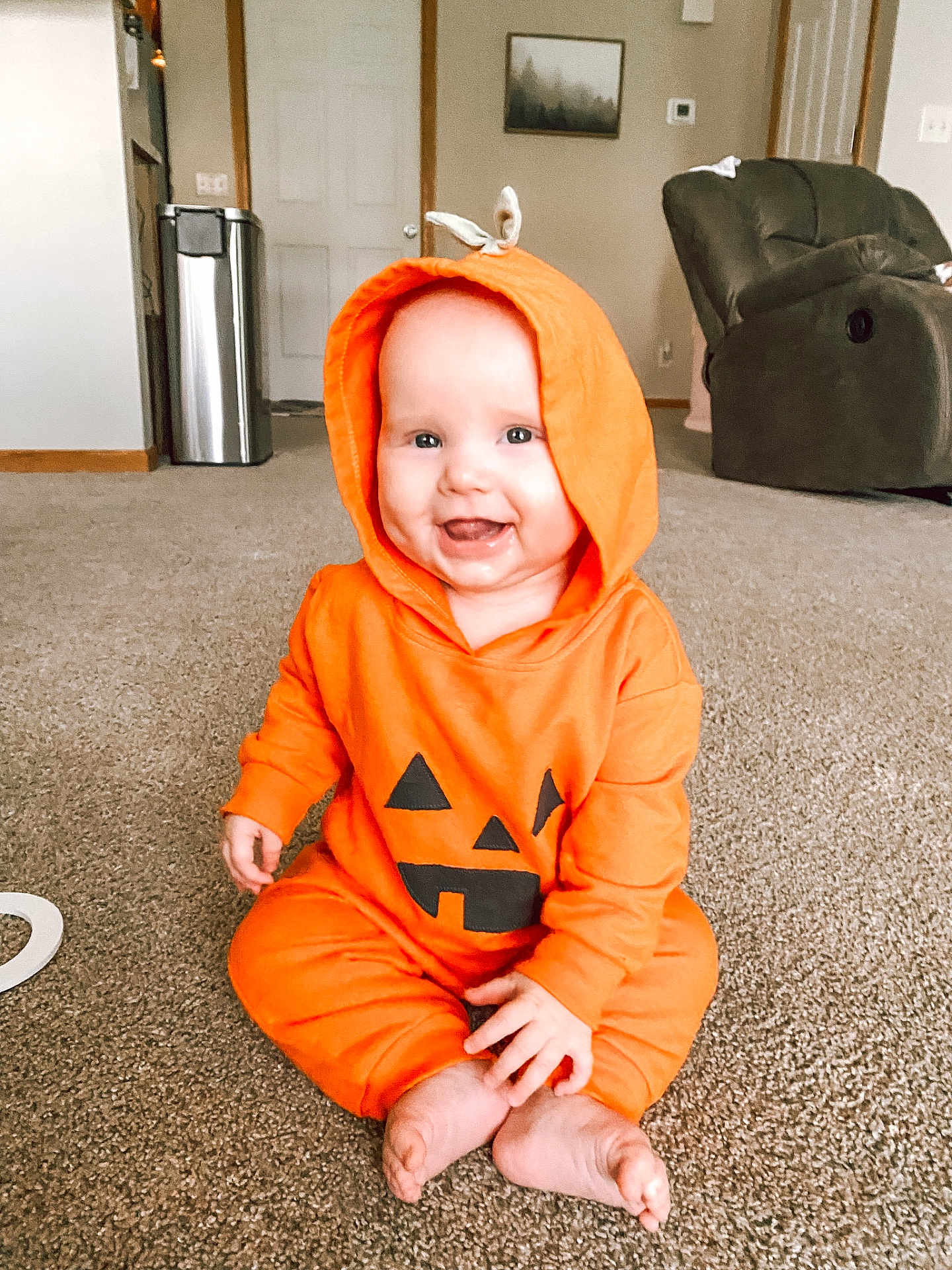 Brae joined the competition — help win amazing prizes! baby, infant, orange_hoodie, pumpkin_costume, smiling, sitting, carpet, living_room, furniture, cozy, hood, cute, child, indoors, happy, face, feet, home, playful, casual