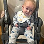 Liam joined the competition — help win amazing prizes! baby, baby_bib, bib, child, clothing, curious, cute, dinosaur_pajamas, face, footwear, high_chair, indoor, infant, person, seat, seatbelt, smiling, socks, wall, wooden_floor