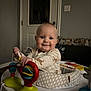 baby, infant, smile, face, toy, activity_center, indoor, door, child, clothing, play, happy, cute, person, furniture, seat, colorful, hand, head, room