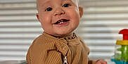 Ryder is registered to the contest to win money with this photo: baby, background, blurred, child, clothing, colorful, cute, face, happy, high_chair, indoor, infant, person, portrait, ribbed, smiling, teeth, toy, window_blinds, young