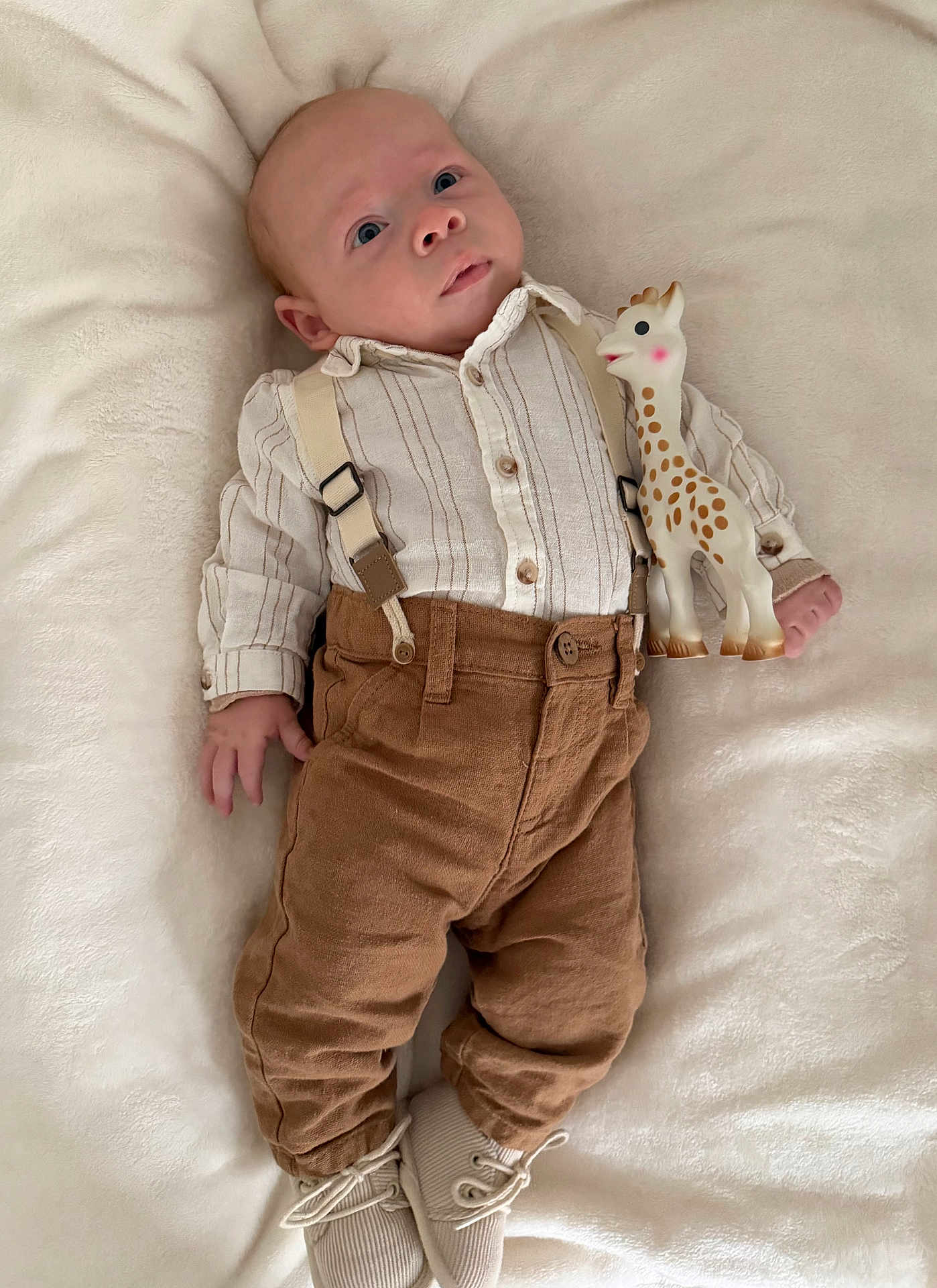 Ezio participe au concours pour gagner de l'argent avec cette photo : baby, infant, toy, giraffe, plush_blanket, clothing, suspenders, pants, shoes, cute, child, portrait, lying_down, soft_texture, indoor, small_toy, looking_up, calm, baby_fashion, newborn
