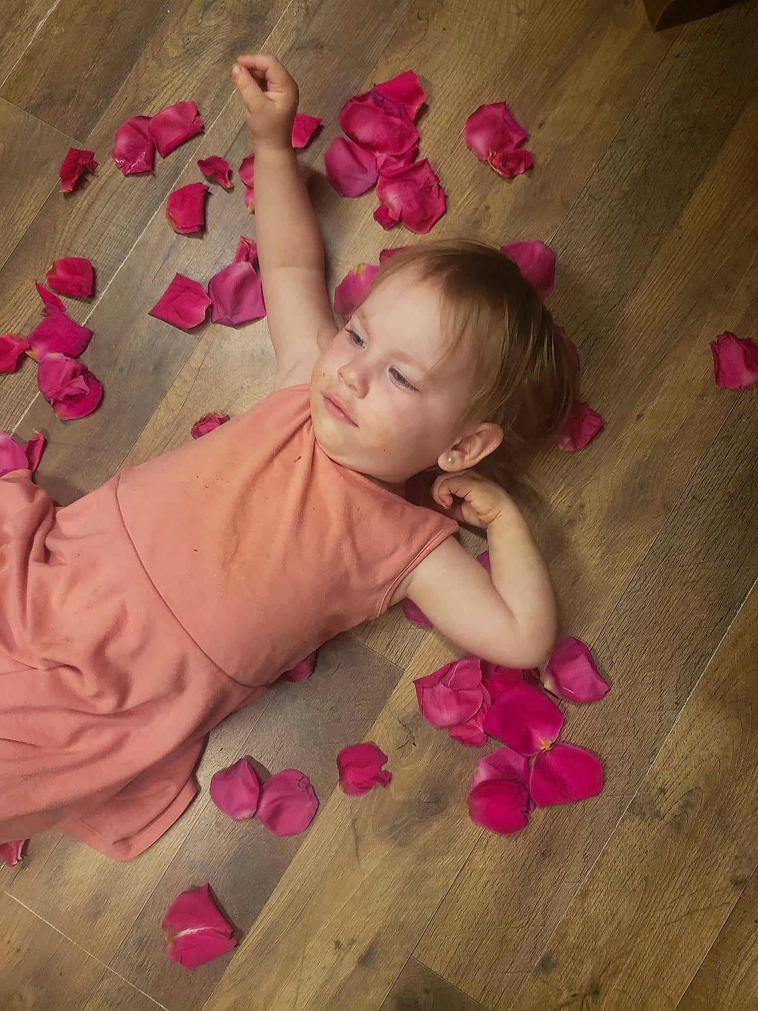 Autumn is registered to the contest to win money with this photo: baby, baby_toddler_clothing, cheek, comfort, facial_expression, finger, floor, flooring, fun, happy, hardwood, human_body, linens, magenta, nail, person, pink, skin, textile, toddler