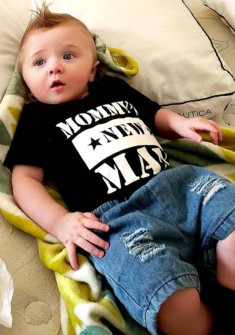 Nicolas is registered to the contest to win money with this photo: baby, baby_products, baby_toddler_clothing, blond, child, comfort, elbow, eye, face, finger, happy, human_leg, knee, neck, person, sleeve, sportswear, surprise, t_shirt, thigh