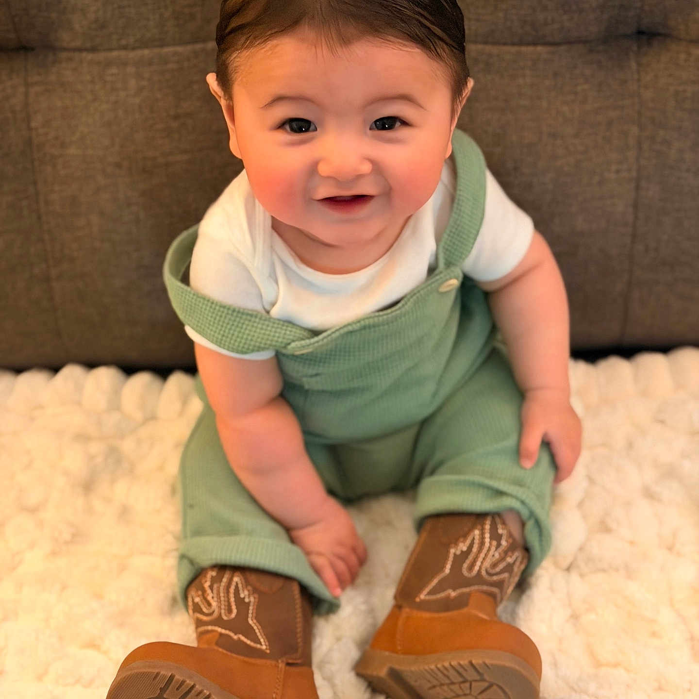 Jameson is registered to the contest to win money with this photo: baby, child, smiling, green_overalls, brown_boots, white_shirt, fluffy_blanket, indoor, cute, happy, sitting, portrait, face, skin, hair, footwear, one_person, infant, young_child, cozy