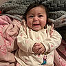 baby, infant, child, smiling, happy, portrait, indoors, blanket, bed, bedding, pink, gray, strawberry, outfit, embroidered, sitting, lying_down, cozy, face, photography