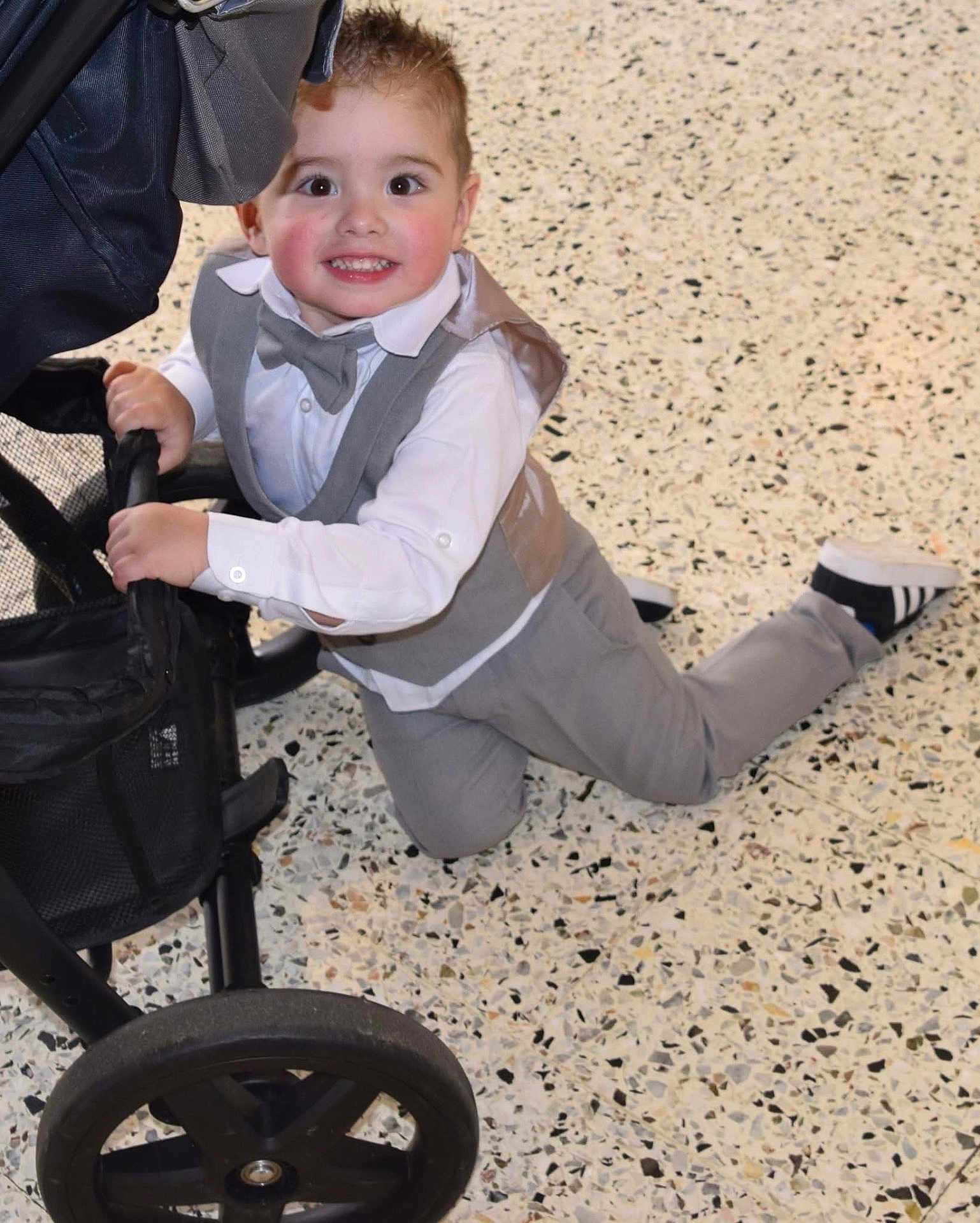 Philippe a rejoint le concours — aidez-le/la à gagner de superbes lots ! child, toddler, boy, smiling, suit, bow_tie, white_shirt, grey_pants, stroller, kneeling, floor, indoor, happy, cute, fashion, baby_shoes, black_shoes, portrait, face, hands
