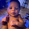 Valencia is registered to the contest to win money with this photo: baby, infant, child, portrait, face, smiling, indoors, home, living_room, sitting, bare_shoulders, arms, hands, eyes, hair, skin, blue_lighting, furniture, floor, photography
