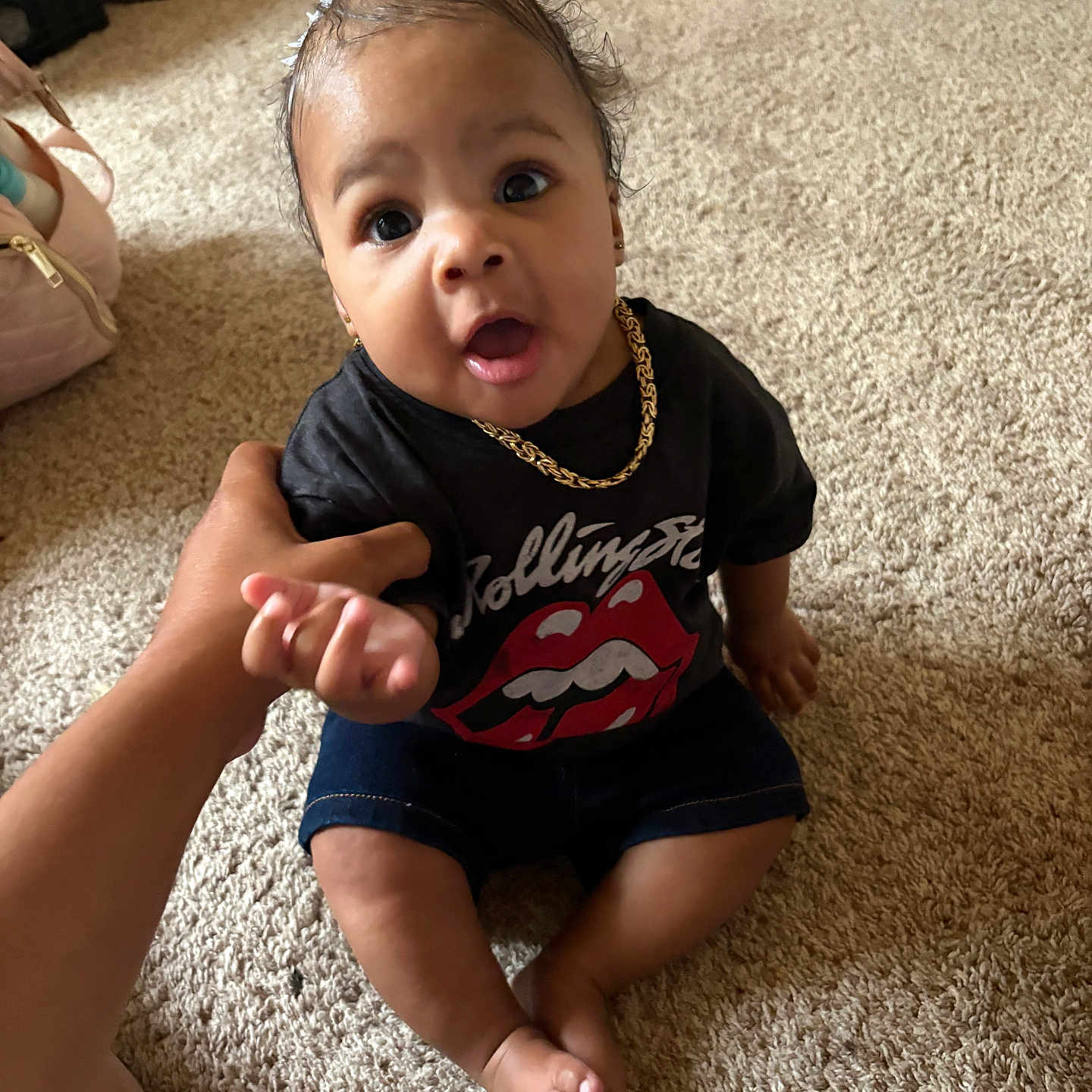 Yzsoulnae is registered to the contest to win money with this photo: baby, carpet, child, curious, cute, expression, floor, gold_chain, hand, holding_arm, indoor, infant, open_mouth, person, red_bow, rolling_stones_tshirt, shorts, sitting, skin, wide_eyes