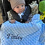 Finley joined the competition — help win amazing prizes! baby, stroller, blanket, hat, pom_poms, child, face, blue_eyes, clothing, toy, plush_toy, infant, warm, cute, comfort, portrait, outside, bundle, soft_texture, seated