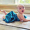 Levi is registered to the contest to win money with this photo: baby, child, tummy, blue_fabric, rug, floor, window, natural_light, indoors, happy, smiling, skin, face, barefoot, cute, infant, expression, portrait, soft_light, home