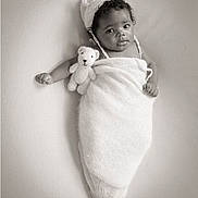 Bless'In is registered to the contest to win money with this photo: adorable, baby, baby_boy, black_and_white, child, cozy, cute, face, hat_with_ears, infant, knitted_hat, knitted_wrap, lying_down, newborn, portrait, smiling, soft_texture, studio, teddy_bear, wrapped