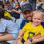 Rhett joined the competition — help win amazing prizes! child, man, crowd, stadium, sports, fan, seating, casual_clothing, hat, glasses, watch, smile, yellow_shirt, facial_hair, family, people, event, spectators, outdoor, daytime