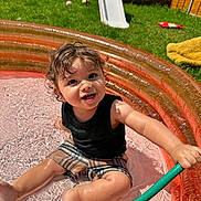 Lucius is registered to the contest to win money with this photo: baby, ball, clothing, face, grass, head, outdoors, person, photography, plant, pool, portrait, shorts, slide, sport, summer, tennis, tennisball, toy, water