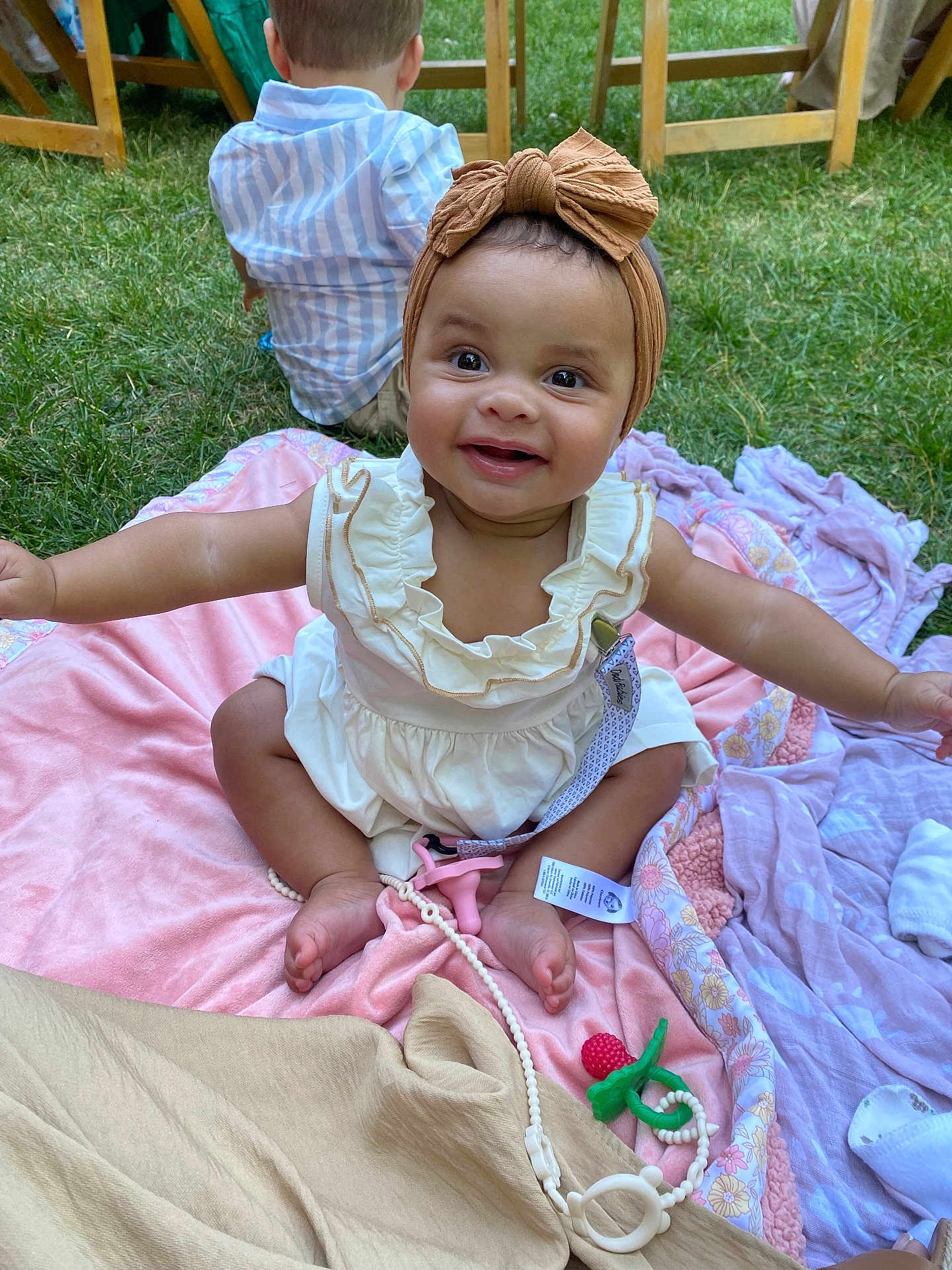 Laila joined the competition — help win amazing prizes! baby, child, girl, smiling, headband, bow, dress, blanket, grass, outdoor, boy, chair, wood, happy, person, playing, picnic, toy, foot, nature
