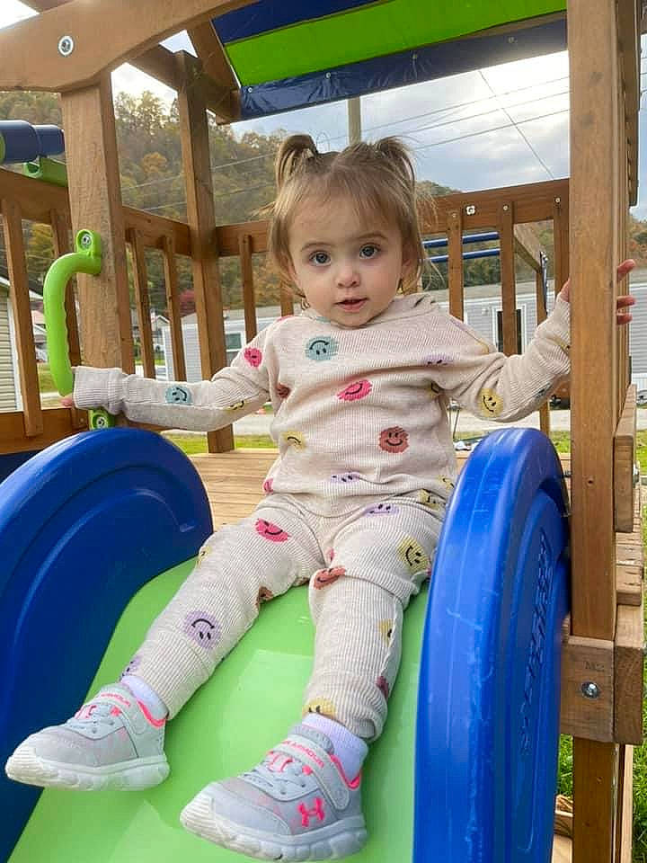 Raelynn is registered to the contest to win money with this photo: automotive_tire, baby_toddler_clothing, child, city, electric_blue, fun, grass, happy, human_settlement, leisure, outdoor_play_equipment, person, playground, public_space, recreation, sitting, tire, toddler, tread, wheel