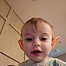 Jocelynne is registered to the contest to win money with this photo: baby, child, infant, portrait, face, ears, elf_like, curious, indoors, warm_lighting, close_up, camera, open_mouth, hair, eyes, shirt, patterned_clothing, tile, ceiling, pet