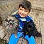 child, boy, dog, pet, smiling, happy, outdoor, wooden_bench, blue_clothing, fluffy_dog, black_dog, gray_dog, nature, grass, casual, portrait, playing, cute, animal, friendship