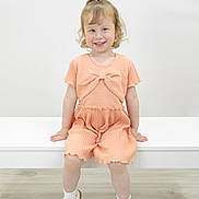 Hollie joined the competition — help win amazing prizes! bench, bow, bright, child, curly_hair, cute, fashion, floor, girl, happy, indoor, minimalist, peach_outfit, playful, portrait, sitting, smiling, white_shoes, white_socks, young