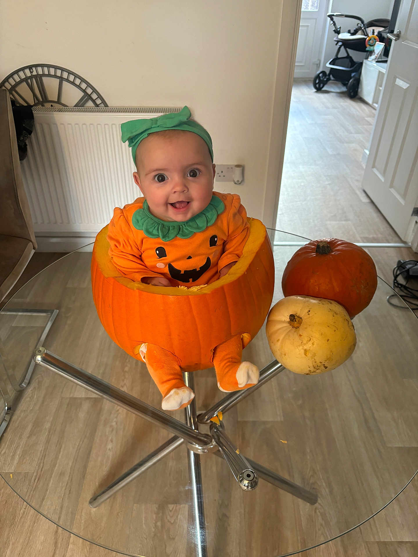 Cali-Rose joined the competition — help win amazing prizes! baby, pumpkin, halloween, costume, table, glass_table, indoor, child, smiling, orange, headband, legs, floor, chair, radiator, door, baby_clothing, happy, festive, decor