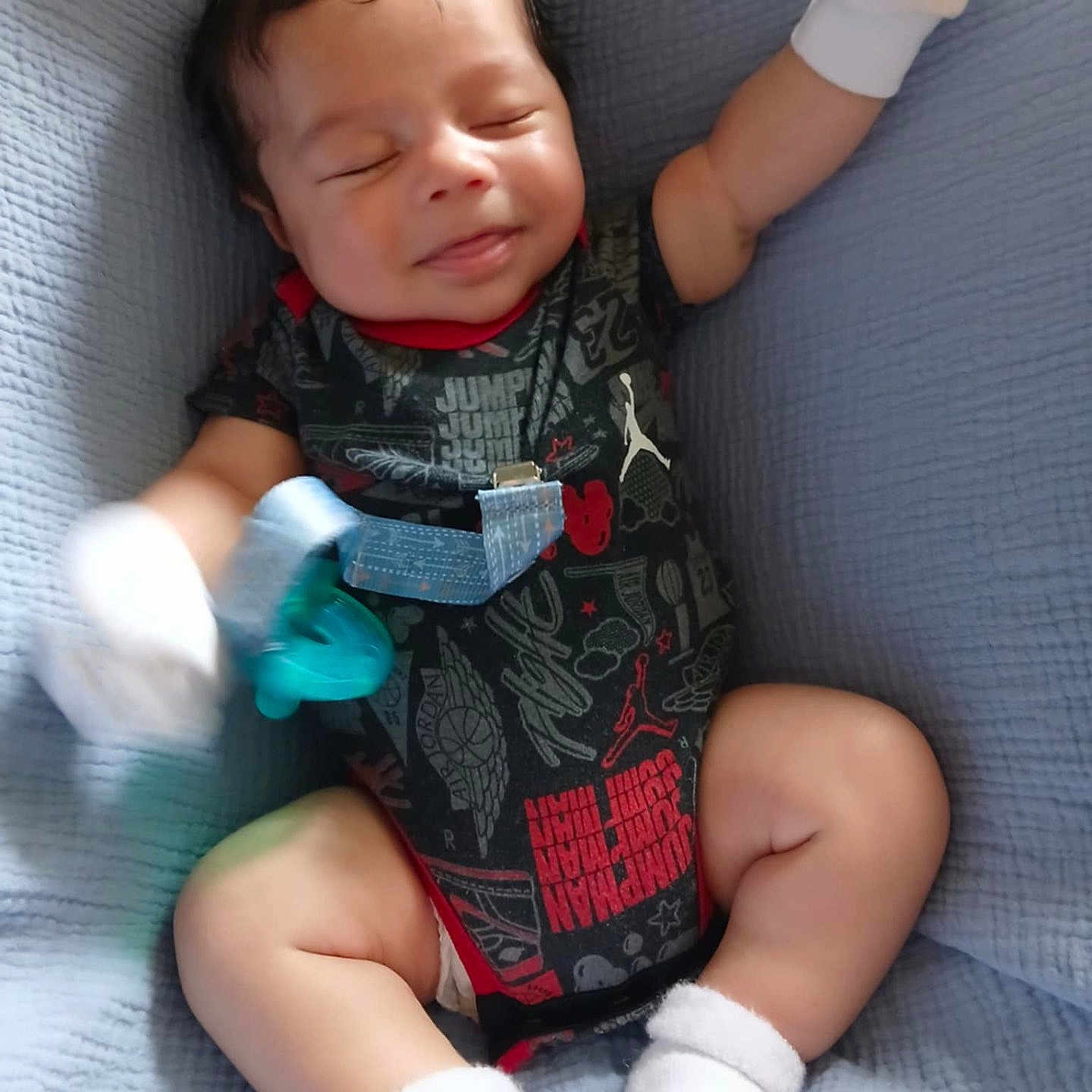 Zayden is registered to the contest to win money with this photo: baby, blanket, child, clothing, comfort, cute, happy, indoor, infant, lying_down, mittens, newborn, onesie, pacifier, person, portrait, relaxed, smiling, socks, soft