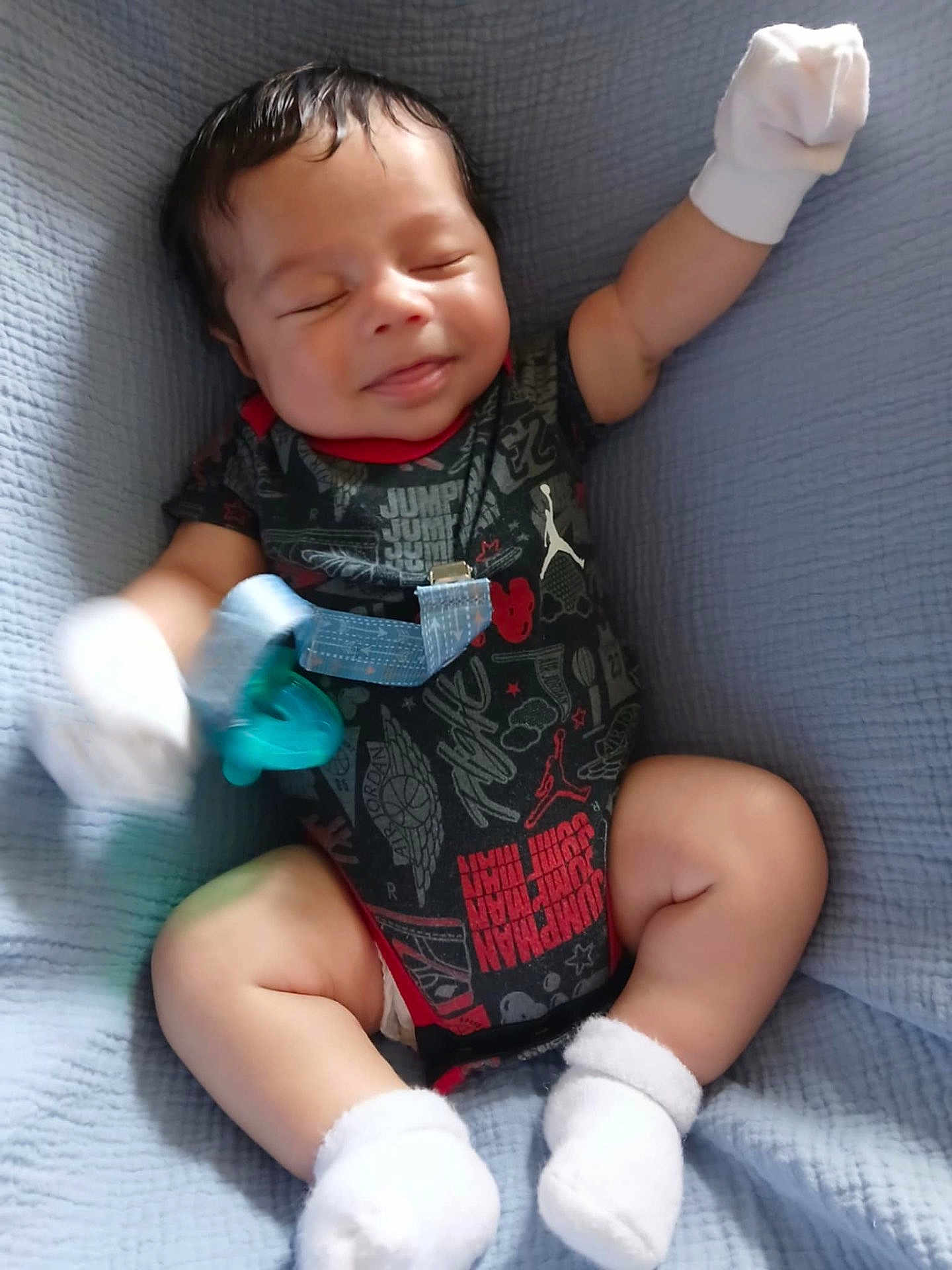 Zayden is registered to the contest to win money with this photo: baby, smiling, onesie, mittens, socks, pacifier, blanket, infant, child, happy, cute, lying_down, clothing, indoor, person, portrait, newborn, soft, comfort, relaxed