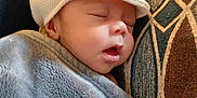 Zayden joined the competition — help win amazing prizes! baby, sleeping, hat, blanket, cushion, face, child, cozy, indoors, rest, peaceful, soft_texture, portrait, closeup, cute, comfort, headwear, nap, infant, warm