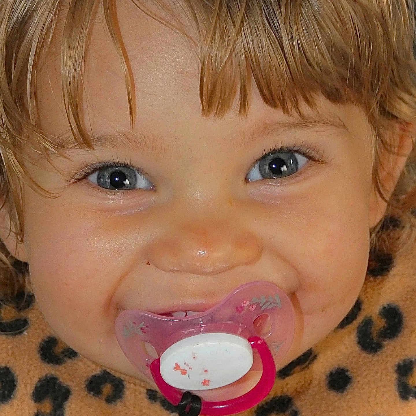Jélyana participe au concours pour gagner de l'argent avec cette photo : baby, blonde_hair, blue_eyes, child, close_up, clothing, cute, eyelashes, face, happy, indoors, infant, leopard_print, pacifier, person, portrait, skin, smile, toddler, young_child